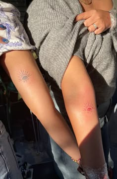 two people with sun tattoos on their legs