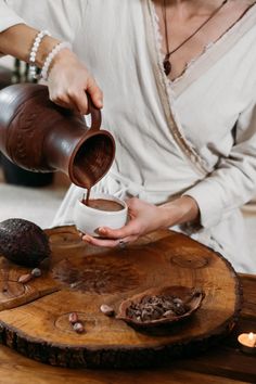 a woman pours coffee into a cup on top of a wooden table next to an acorn