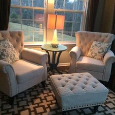 a living room with two chairs and a footstool in front of a window