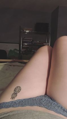 a woman laying on top of a bed with her legs crossed and tattoos on her stomach