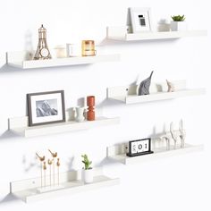 three white shelves with pictures, candles and other items on them are arranged in the same pattern