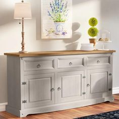 the sideboard is painted white and has drawers on each side, along with two lamps