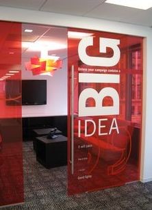 an office cubicle with red glass walls and chairs