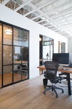 an office with wooden floors and glass doors on the walls is featured in this instagram