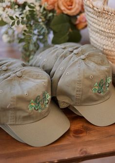 three hats sitting on top of a wooden table next to a basket with flowers in it