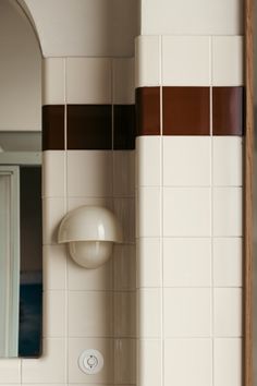 a bathroom with white and brown tiles on the walls