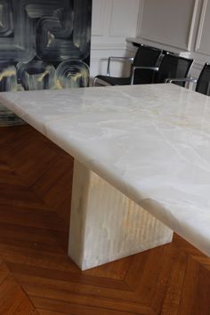 a white marble table with black chairs in the backgrounge and wood flooring