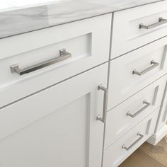 a white kitchen with marble counter tops and drawers