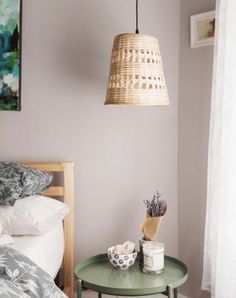 a bedroom with a bed, table and hanging lamp in it's centerpiece