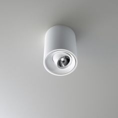 an overhead view of a white light fixture on a gray wall with a circular lens