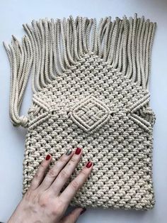 a woman's hand holding onto a crocheted purse