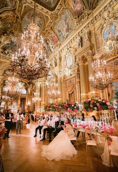 the bride and groom are sitting at their wedding reception in an ornately decorated ballroom