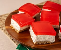 several pieces of red and white cake on a wooden plate next to a green napkin