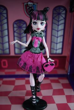 a doll dressed in pink and black holding a heart shaped purse on a checkered floor