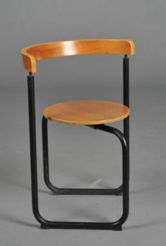 a wooden chair with black metal legs and a round seat on the back, against a gray background