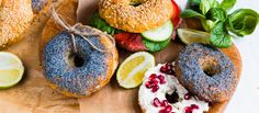 doughnuts with different toppings on a wooden board next to lemon slices and strawberries