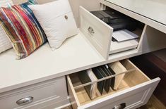 a white desk with drawers and pillows on it