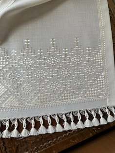 a white table cloth with tassels and beads on it sitting on a wooden surface