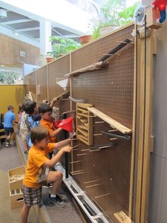 two young boys are playing with some sort of object in a museum display case while others look on