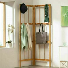 a room divider with several coats and bags hanging from it's sides, in front of a window