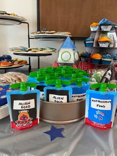 an assortment of food is displayed on a table with plastic cups and spoons in front of it