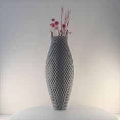 a vase with some flowers in it sitting on a white table and lit by a light