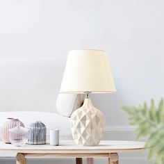 a table with a lamp on top of it next to a couch and potted plant