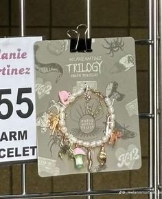 a sign that is hanging on a metal fence next to a tag with some charms