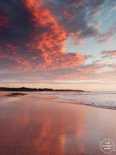 the sky is reflected in the wet sand on the beach at sunset, with people walking along the water's edge