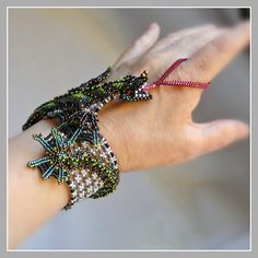 a woman's hand holding three bracelets with beads on each wrist and an arrow in the middle