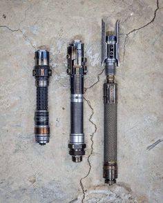 three different types of flashlights sitting on top of a cement floor next to each other