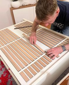 a man is working on some wood strips that are being cut into squares and placed on top of the table