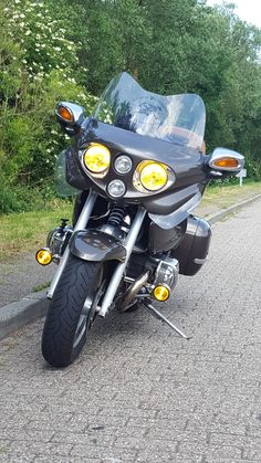 the motorcycle is parked on the side of the road next to the grass and trees