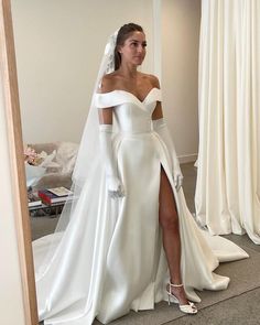 a woman in a white wedding dress is standing near a mirror with her leg on the floor