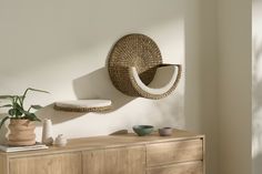 a rattan chair hanging on the wall next to a wooden dresser and potted plant