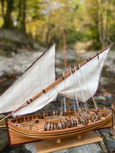 a model sailboat is sitting on some rocks