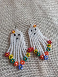 white beaded earrings with multi colored beads on top of a fabric cloth covered surface