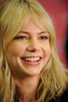 a woman with blonde hair smiling at the camera