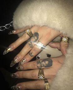 two hands with tattoos and rings on them