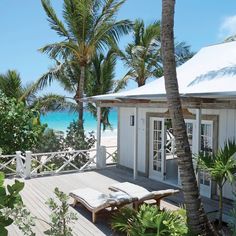 a white house on the beach with palm trees