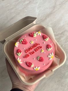 a pink birthday cake with strawberries on it in a plastic container that says happy birthday