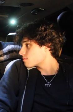 a young man sitting in the back seat of a car with his head turned to the side