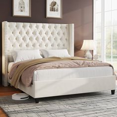 a white bed sitting on top of a wooden floor next to a lamp and window