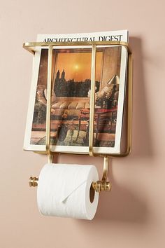 a toilet paper dispenser mounted to the side of a wall with pictures on it