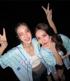 two young women posing for the camera with their hands in the air