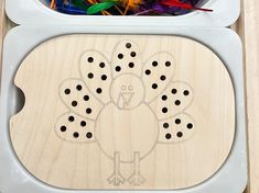 a wooden turkey cutout sitting on top of a table with crayons in the background