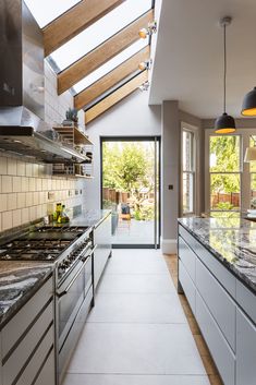 a kitchen with an oven, stove and sink under a skylight that is open to the outside