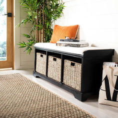 a black bench with baskets on it in front of a door and a potted plant