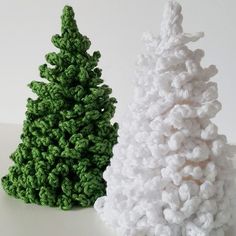 two crocheted christmas trees sitting next to each other on a white counter top