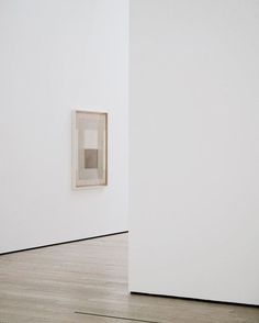 an empty room with two paintings on the wall and one in the middle of the room